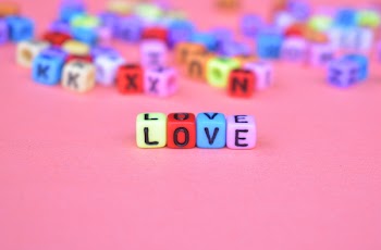 Selective Focus Photo of Green, Red, Blue, and Pink Love Bead on Pink Surface