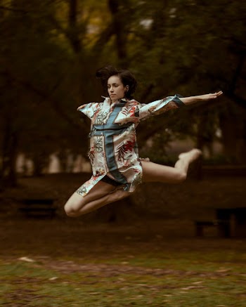 Selective Focus Photo of Jumping Woman Wearing Blue and White Cross-printed Top