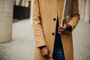 Selective Focus Photo of Man in Brown Overcoat Carrying a Laptop