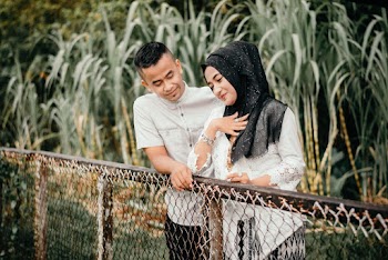 Selective Focus Photo of Man in White Shirt Next to  Woman in Black Hijab Leaning on Fence