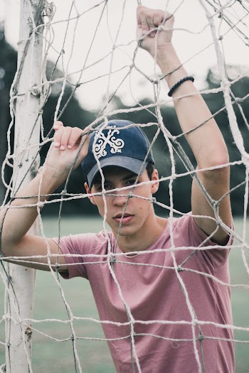Selective Focus Photo of Man Leaning on Soccer Goal Net