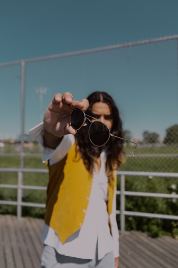 Selective Focus Photo of Man Posing While Holding out His Sunglasses