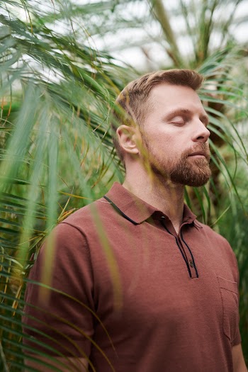 Selective Focus Photo of Man Standing Near Green Plants