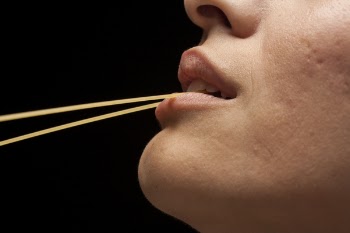 Selective Focus Photo of Person Biting Pasta
