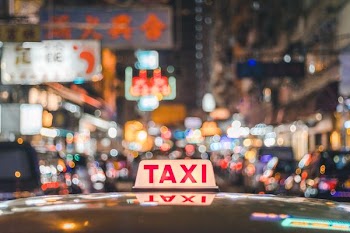 selective focus photo of red and white Taxi sign