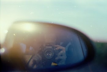 Selective Focus Photo of Side Mirror With Reflection of Person Holding Black Dslr Camera