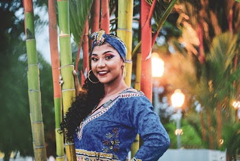 Selective Focus Photo of Smiling Woman in Traditional African Wear Standing Near Trees