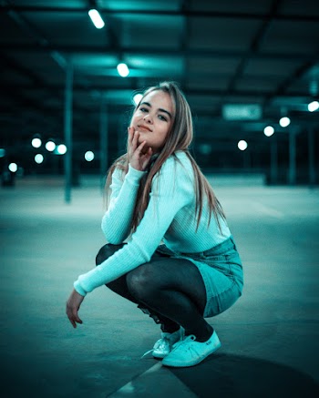 Selective Focus Photo of Smiling Woman Squat Posing in Empty Parking Lot