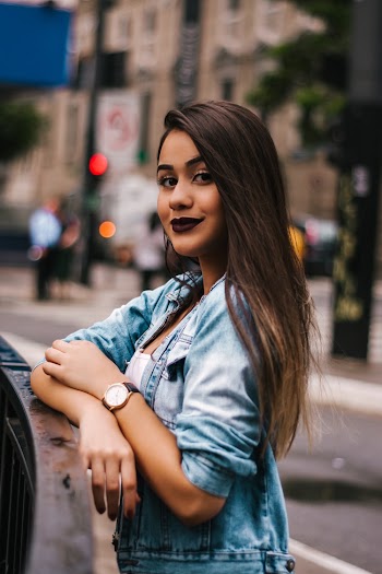 Selective Focus Photo of Smiling Woman Standing Beside Black Metal Railing