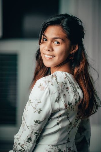 selective focus photo of smiling woman wearing white and pink floral long-sleeved dress