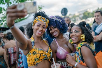 Selective Focus Photo of Smiling Women Taking a Selfie With a Crowd of People In the Background