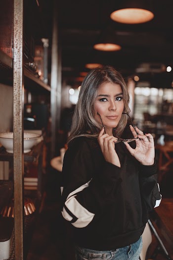 Selective Focus Photo of Standing Woman in Black and White Sweatshirt Posing With Glasses