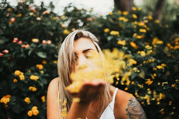 Selective Focus Photo of Woman Blowing Petals