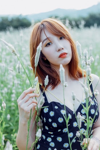 Selective Focus Photo of Woman in Black Floral Top Standing Alone in Grass Field Posing