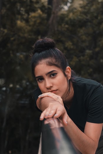 Selective Focus Photo of Woman in Black T-shirt Resting Head on Metal Railing