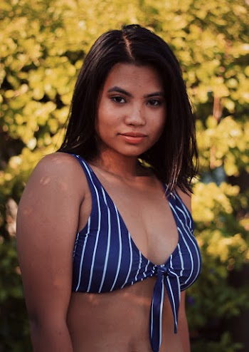 Selective Focus Photo of Woman in Blue Bikini Top Posing With Green-leafed Hedge in the Background