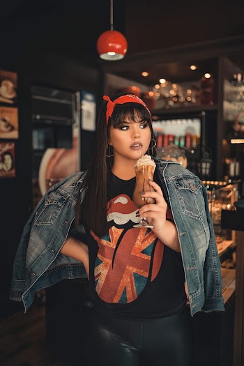 Selective Focus Photo of Woman in Blue Denim Jacket Posing With a Glass of Frappe Coffee While Looking Away
