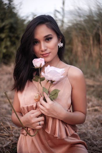 Selective Focus Photo of Woman in Brown V-neck Spaghetti-strap Dress Posing While Holding Flowers