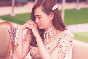 Selective Focus Photo of Woman in Floral Top Sitting at a Table With Her Eyes Closed