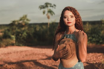 Selective Focus Photo of Woman in Green Dress Posing While Holding Sun Hat Against Her Chest