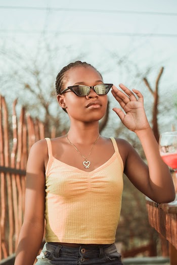 selective Focus Photo of Woman in Orange Top and Black Sunglasses Posing