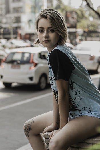 Selective Focus Photo of Woman in Teal and Black T-shirt Sitting on Concrete Edge