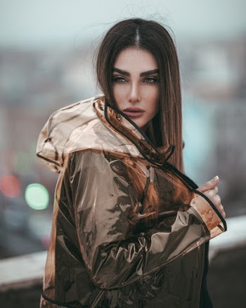 Selective Focus Photo of Woman in Transparent Raincoat Posing While Looking Away
