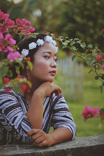 Selective Focus Photo of Woman in White Flower Crown Leaning on Stone Railing While Looking Away