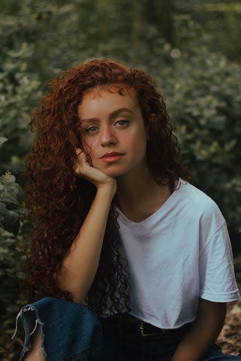 Selective Focus Photo of Woman in White T-shirt Posing With Green Plants in the Background