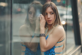 Selective Focus Photo of Woman Leaning on Glass Wall