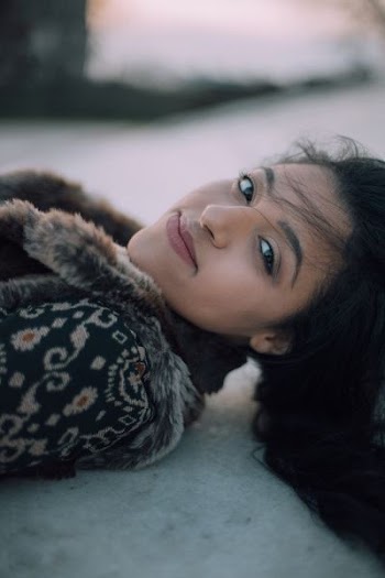selective focus photo of woman lying on ground smiling