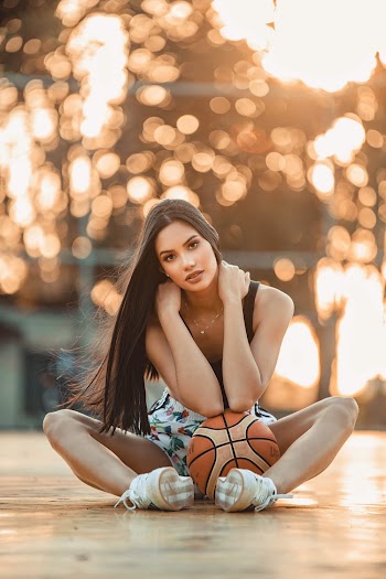 Selective Focus Photo of Woman Siting on the Floor with a Basketball Posing