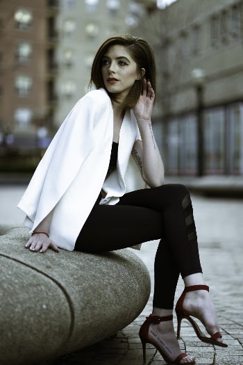 Selective Focus Photo of Woman Sitting on Concrete Block Posing While Looking Away