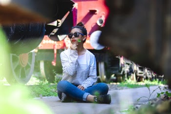 Selective Focus Photo of Woman Sitting on Gray Concrete Ground Posing