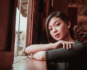 Selective Focus Photo of Woman Standing in Front of an Open Window