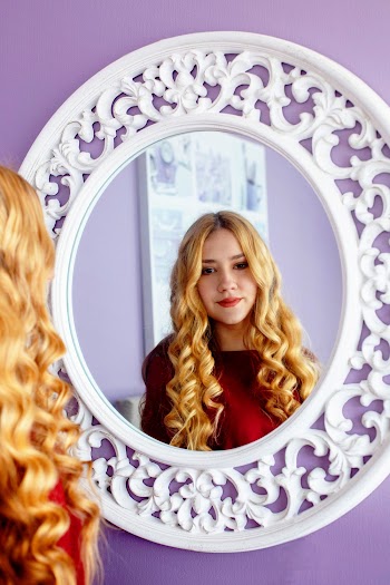 Selective Focus Photo Of Woman Standing In Front Of Round White-framed Mirror