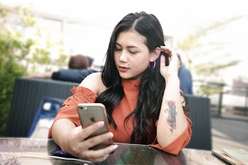 Selective Focus Photo of Woman Using Smartphone While Sitting By Table