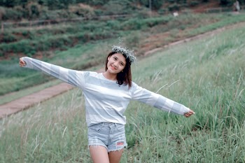 Selective Focus Photo of Woman Wearing Gray and White Striped Sweatshirt Standing on Green Grass Fields