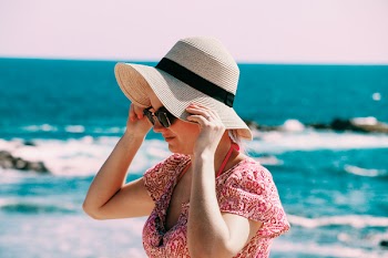 Selective Focus Photo of Woman Wears Beige Sun Hat Stand Behind Body of Water a Daytime