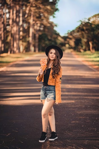 Selective Focus Photo Woman Holding a Lollipop Standing in the Middle of a Road Posing