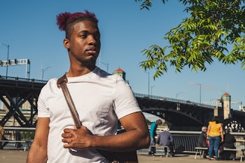 Selective focus  photography of a man wearing white crew-neck t-shirt carrying brown leather bag