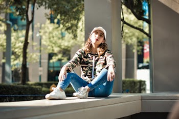 Selective focus photography of a woman sitting down  on white Concrete 