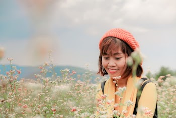 Selective Focus Photography of a Woman Standing Near Flowers