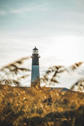 selective focus photography of blue lighthouse under white clouds