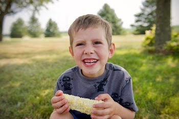 Selective Focus Photography Of Boy Holding Corn While Smiling