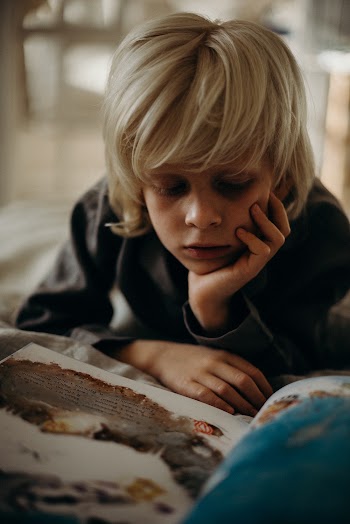 Selective Focus Photography of Boy Resting His Head on His Left Palm