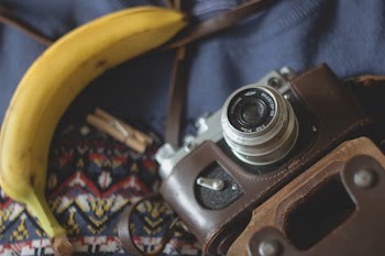 selective focus photography of camera beside banana