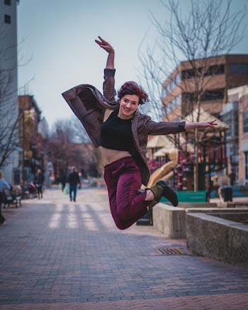 Selective Focus Photography of Jumping Woman on Pathway
