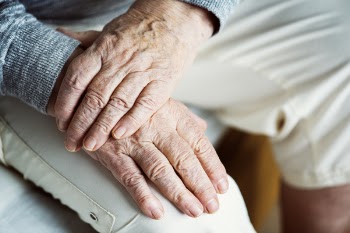 Selective Focus Photography of Left Hand on Top of Right Hand on White Pants