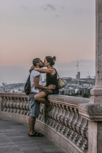 Selective Focus Photography of Man and Woman Kissing on Railings